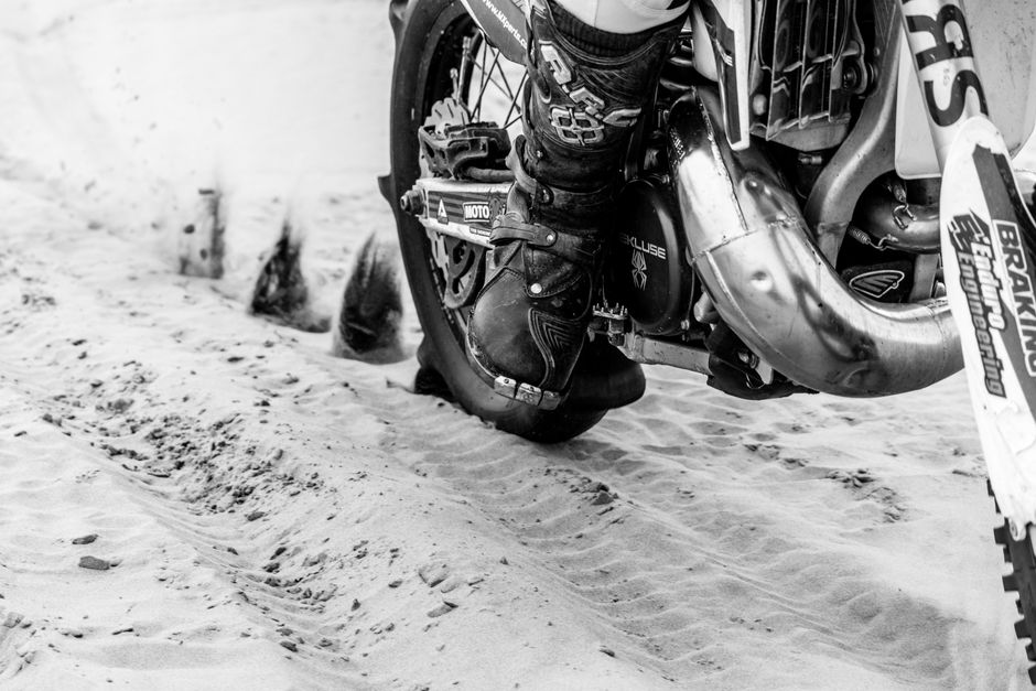 Close-up of a dirt bike tearing through sandy terrain, showcasing detailed motion and texture.